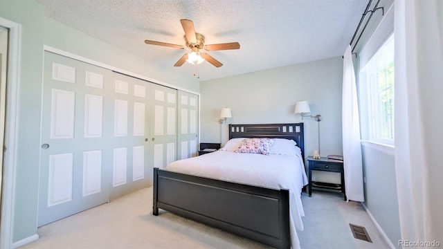 carpeted bedroom featuring multiple windows, a textured ceiling, a closet, and ceiling fan