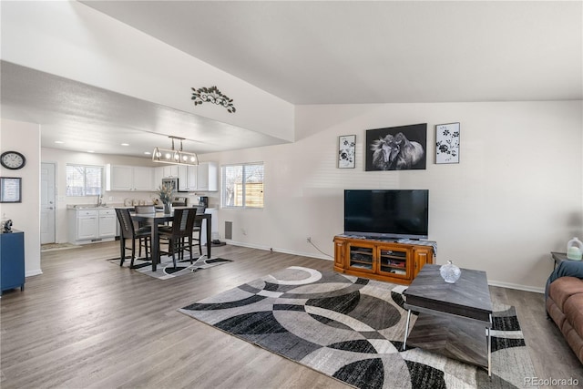 living area with lofted ceiling, light wood-style flooring, and baseboards