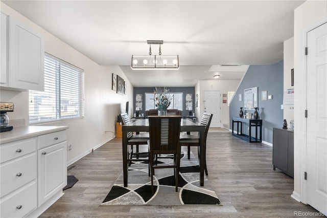 dining room with a chandelier, wood finished floors, visible vents, and baseboards