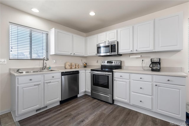 kitchen with visible vents, dark wood-style flooring, stainless steel appliances, white cabinetry, and a sink