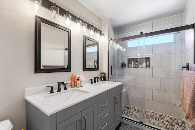 full bath featuring double vanity, a stall shower, a sink, and toilet