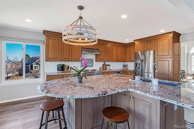 kitchen featuring light stone countertops, appliances with stainless steel finishes, a breakfast bar, and a sink