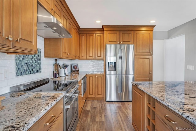 kitchen with brown cabinets, under cabinet range hood, stainless steel appliances, and wood finished floors