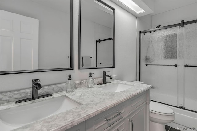 bathroom with enclosed tub / shower combo, double vanity, a sink, and toilet