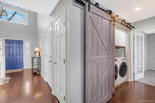 washroom featuring dark wood-style floors, a barn door, a high ceiling, and baseboards