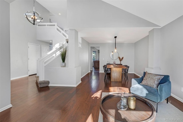 living area featuring baseboards, a towering ceiling, stairway, wood finished floors, and an inviting chandelier