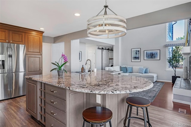 kitchen featuring a barn door, light stone counters, dark wood-type flooring, open floor plan, and stainless steel refrigerator with ice dispenser