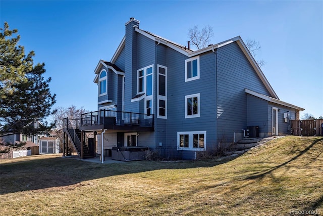 back of property featuring stairway, a hot tub, a deck, central air condition unit, and a lawn