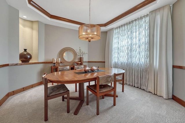 dining room with light carpet, baseboards, a tray ceiling, and ornamental molding