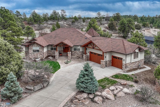view of front of home featuring stone siding, covered porch, an attached garage, stucco siding, and concrete driveway