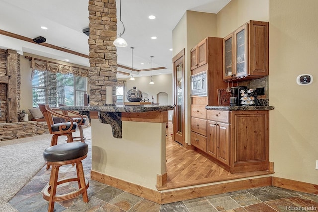 kitchen with decorative columns, baseboards, a kitchen breakfast bar, brown cabinetry, and recessed lighting