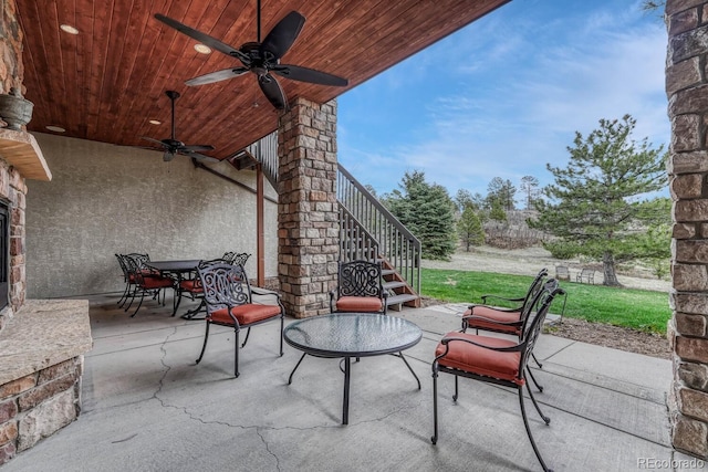 view of patio with stairs, a ceiling fan, and outdoor dining space