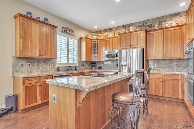 kitchen with a breakfast bar, wood finished floors, appliances with stainless steel finishes, and a kitchen island