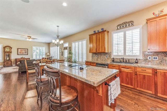 kitchen with a kitchen island, black electric stovetop, open floor plan, stainless steel dishwasher, and a sink