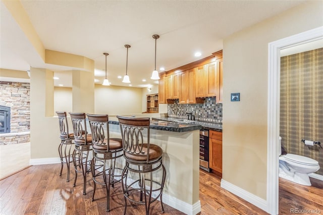 kitchen with decorative backsplash, dark countertops, a kitchen breakfast bar, and wood-type flooring