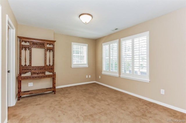 spare room with visible vents, baseboards, and light colored carpet