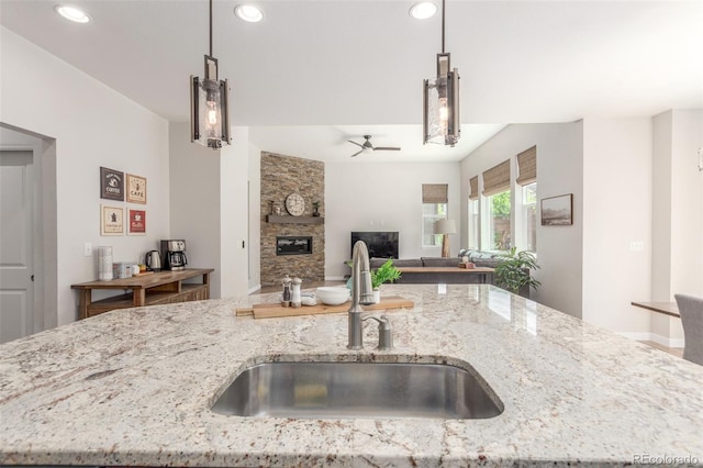 16694 Miners Way, Broomfield, CO 80023 - kitchen featuring a fireplace, ceiling fan, light stone counters, recessed lighting, and decorative light fixtures