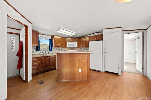 kitchen featuring vaulted ceiling, a center island, light wood-type flooring, and white appliances