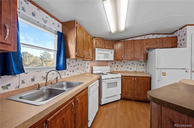 kitchen featuring vaulted ceiling, light hardwood / wood-style floors, sink, white appliances, and a textured ceiling