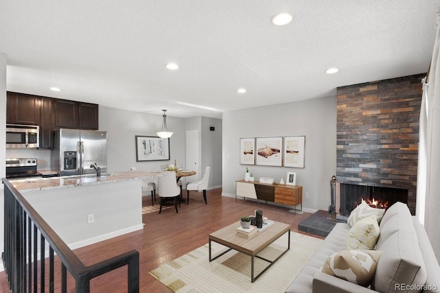 living room featuring a textured ceiling, dark hardwood / wood-style floors, sink, and a fireplace