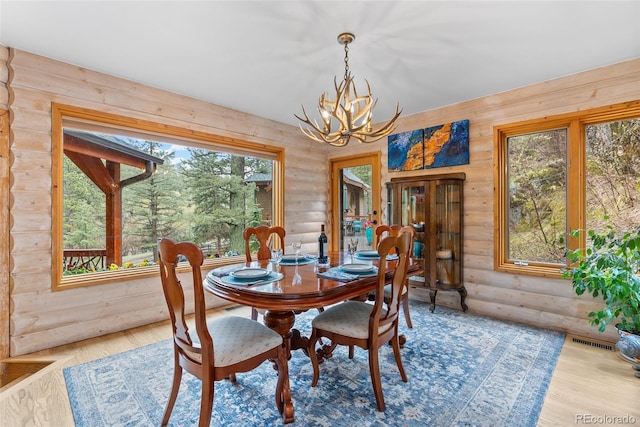 dining space with a chandelier, wood walls, and wood finished floors