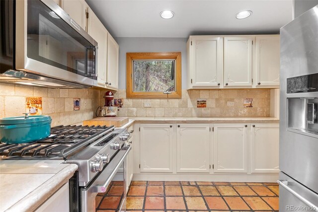 kitchen with appliances with stainless steel finishes, light countertops, white cabinetry, tasteful backsplash, and recessed lighting