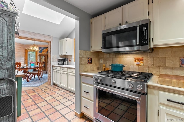 kitchen with appliances with stainless steel finishes, a chandelier, light countertops, decorative backsplash, and white cabinetry