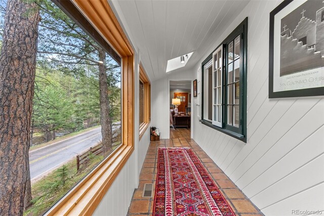 hall featuring a skylight, healthy amount of natural light, and wood walls