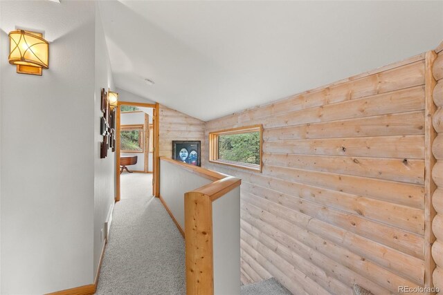 hall featuring vaulted ceiling, carpet, and an upstairs landing