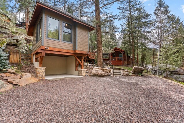 view of side of property featuring a patio, stucco siding, stairway, gravel driveway, and fence