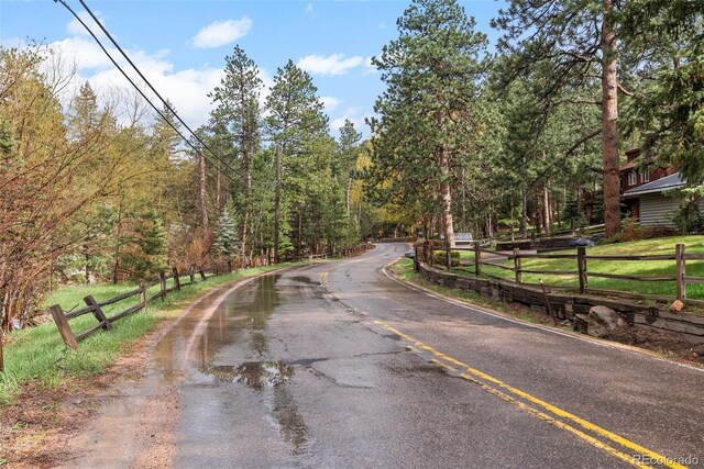view of asphalt street with a view of trees