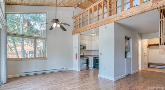 unfurnished living room with plenty of natural light, wood ceiling, baseboard heating, and light wood-style flooring