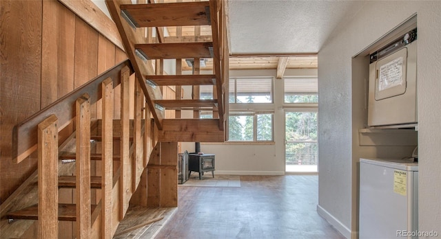 interior space featuring stacked washer / drying machine, a wood stove, and baseboards