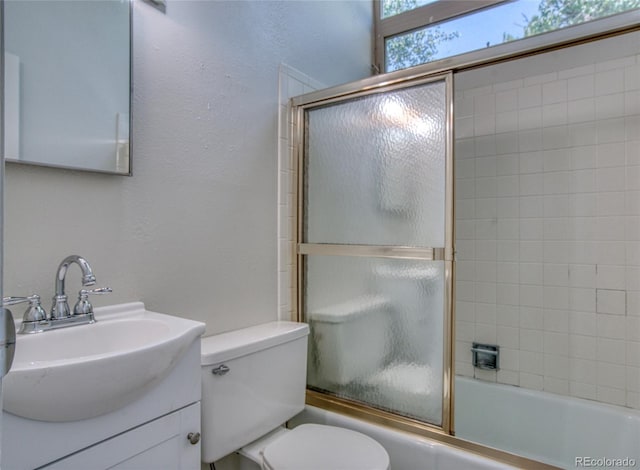 full bathroom with enclosed tub / shower combo, a textured wall, toilet, and vanity