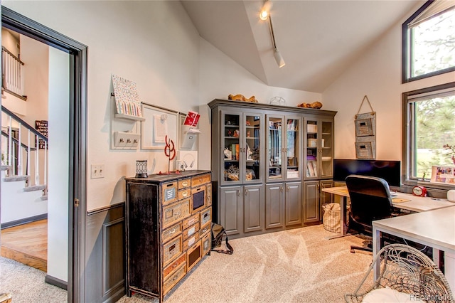 carpeted office space featuring track lighting and high vaulted ceiling