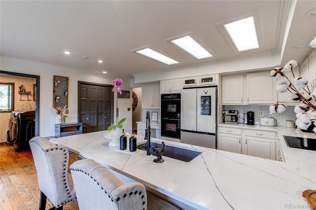 kitchen with double oven, washer / clothes dryer, sink, white cabinets, and white fridge