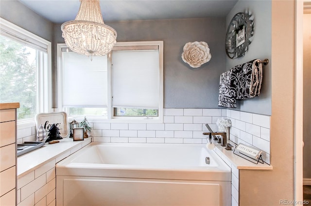 bathroom featuring a bath, a chandelier, and a wealth of natural light