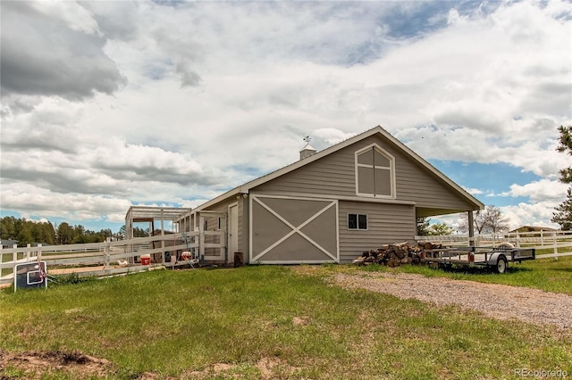 view of barn with a yard, fence, and driveway