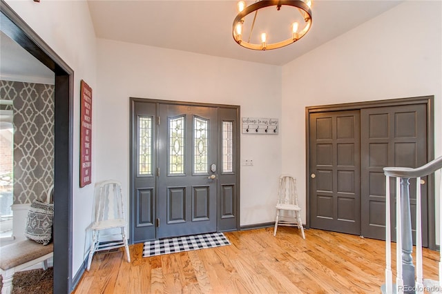 foyer featuring a chandelier, baseboards, stairway, and light wood finished floors