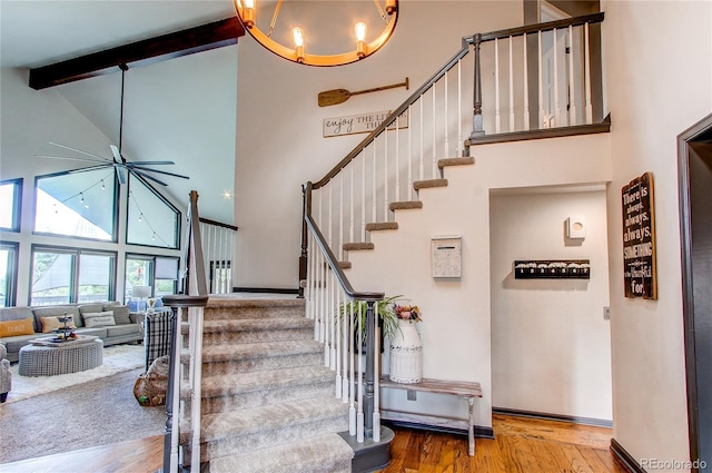 stairway featuring high vaulted ceiling, beamed ceiling, wood finished floors, and baseboards