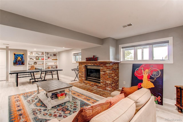 living area featuring light wood-style floors, baseboards, a fireplace, and visible vents