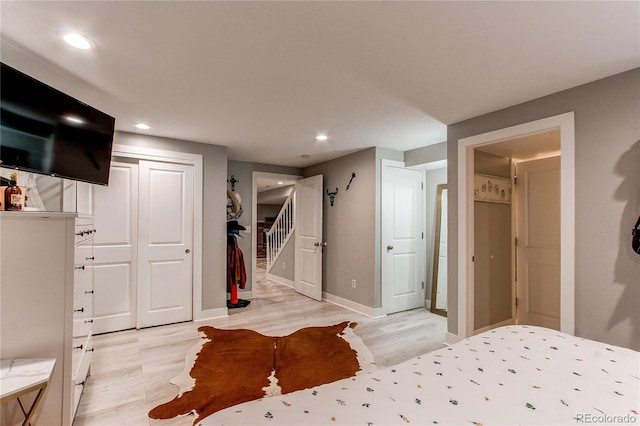 bedroom with recessed lighting, a closet, light wood-style flooring, and baseboards