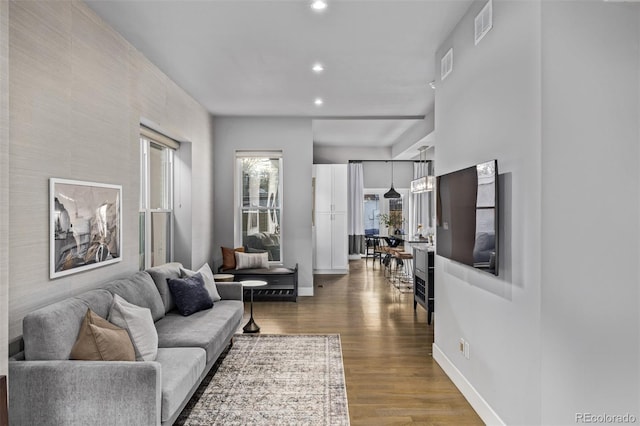 living area with recessed lighting, wood finished floors, visible vents, and baseboards