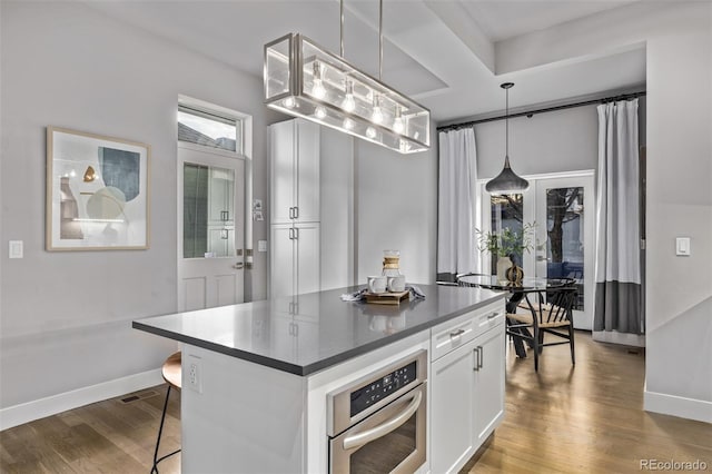 kitchen featuring dark countertops, wood finished floors, oven, and white cabinetry