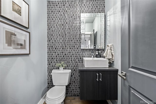 bathroom with decorative backsplash, tile walls, toilet, and vanity