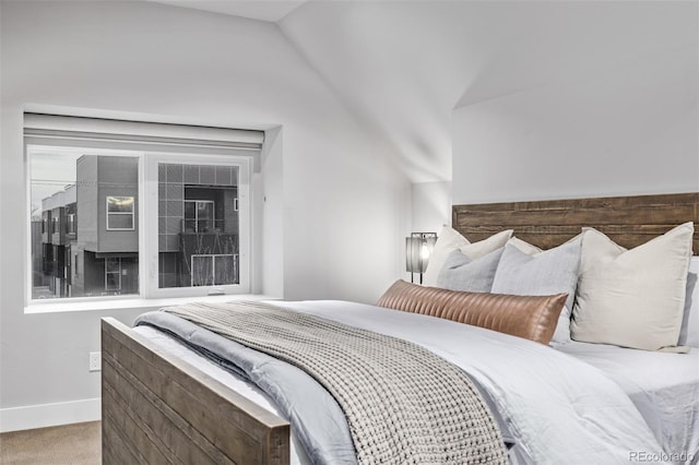 carpeted bedroom with vaulted ceiling and baseboards