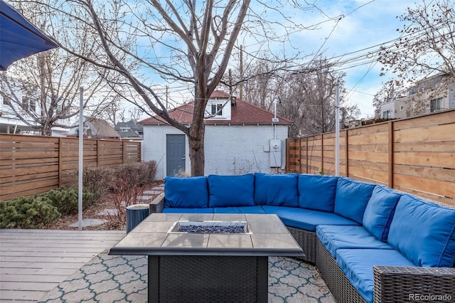 deck featuring a fenced backyard, an outdoor structure, and an outdoor living space with a fire pit