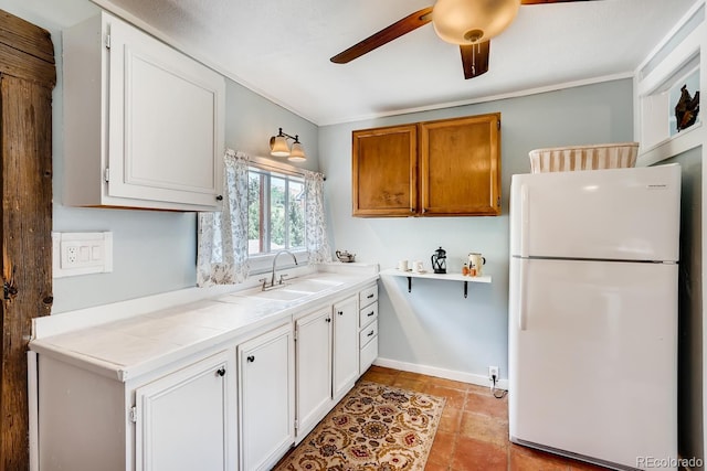 kitchen featuring white cabinets, white fridge, tile countertops, and sink