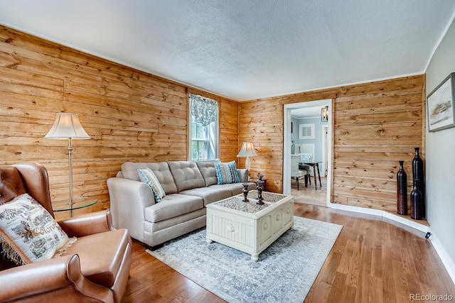 living room with wooden walls, light hardwood / wood-style flooring, and a textured ceiling