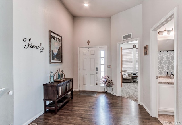 foyer featuring visible vents, a towering ceiling, baseboards, and dark wood-style flooring